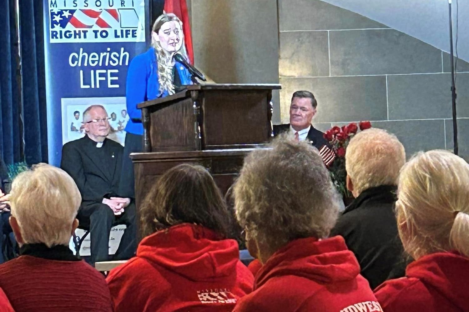 Monsignor David Cox, pastor of St. Stanislaus Parish in Wardsville and St. Margaret of Antioch Parish in Osage Bend (left, seated) listens to a speaker during Missouri Right to Life’s Pro-Life Action Day in the State Capitol.